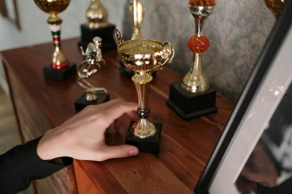 Person adjusting trophy on a shelf of awards
